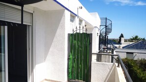 Een wit gebouw met een groene poort, een balkon en een spiraaltrap.