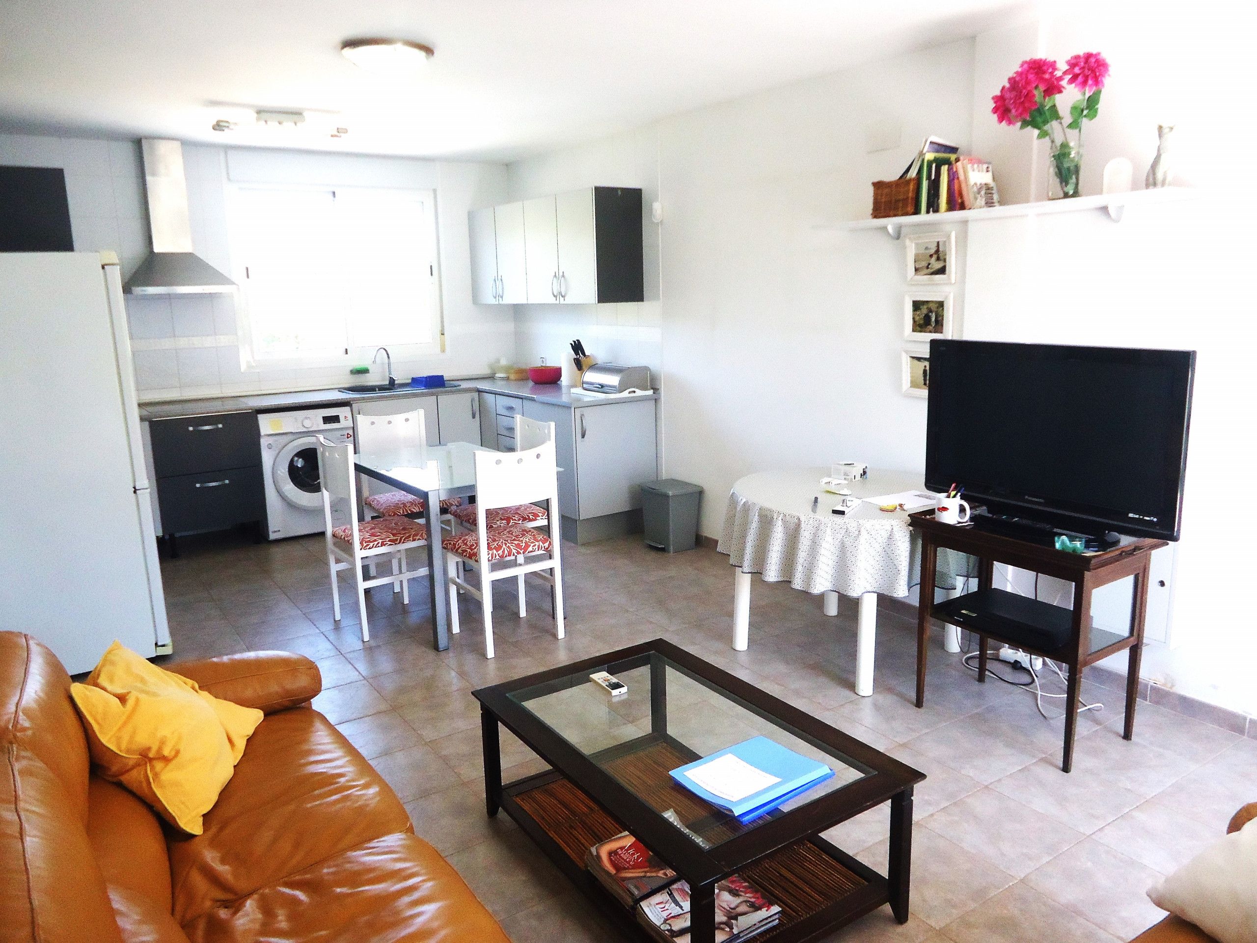 Un espacio habitable compacto con cocina, comedor y televisor.