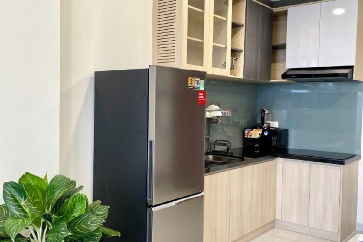 A compact kitchen with a stainless steel refrigerator, a microwave, and a sink.