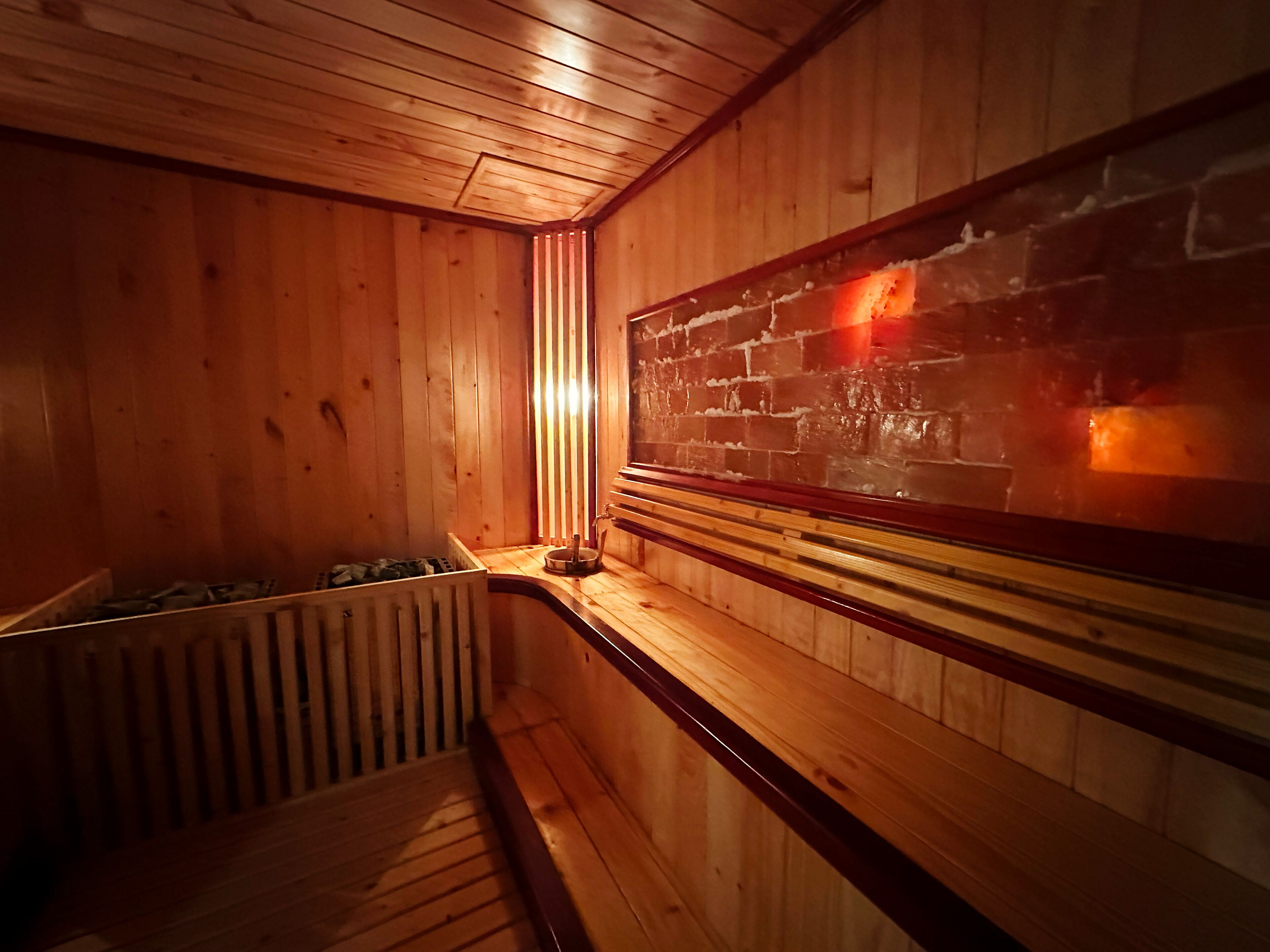 A wooden sauna with a bench, a wall-mounted heater, and a radiator.