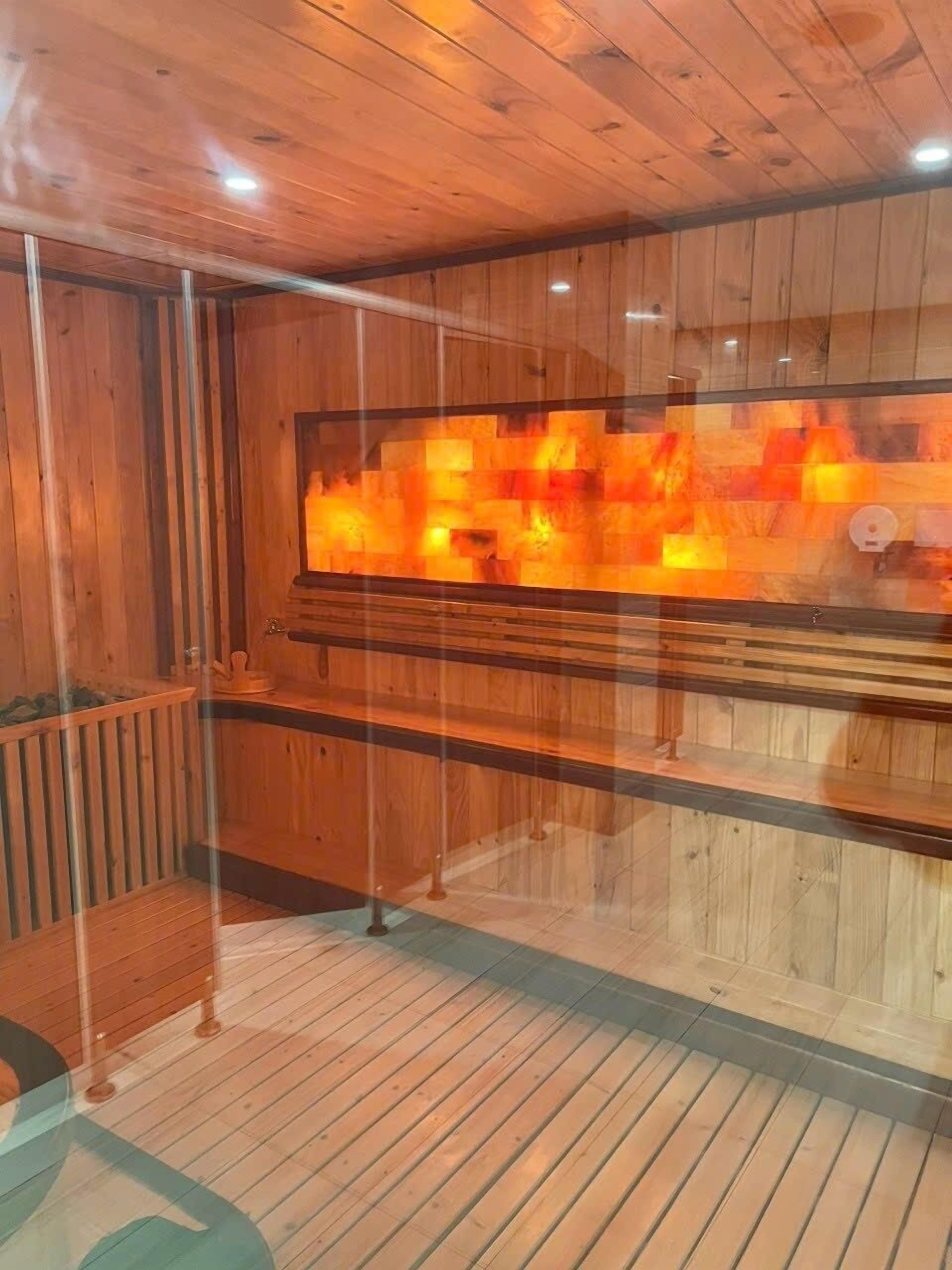 Uma sala de sauna com paredes de madeira e divisória de vidro.