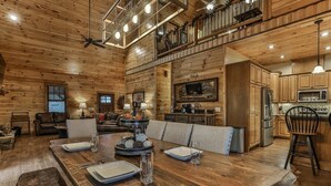 A spacious dining area with a wooden table set for four, a kitchen with modern appliances, and a cozy seating area with a fireplace. - North Georgia Hideaway | Ellijay, GA (Ellijay)