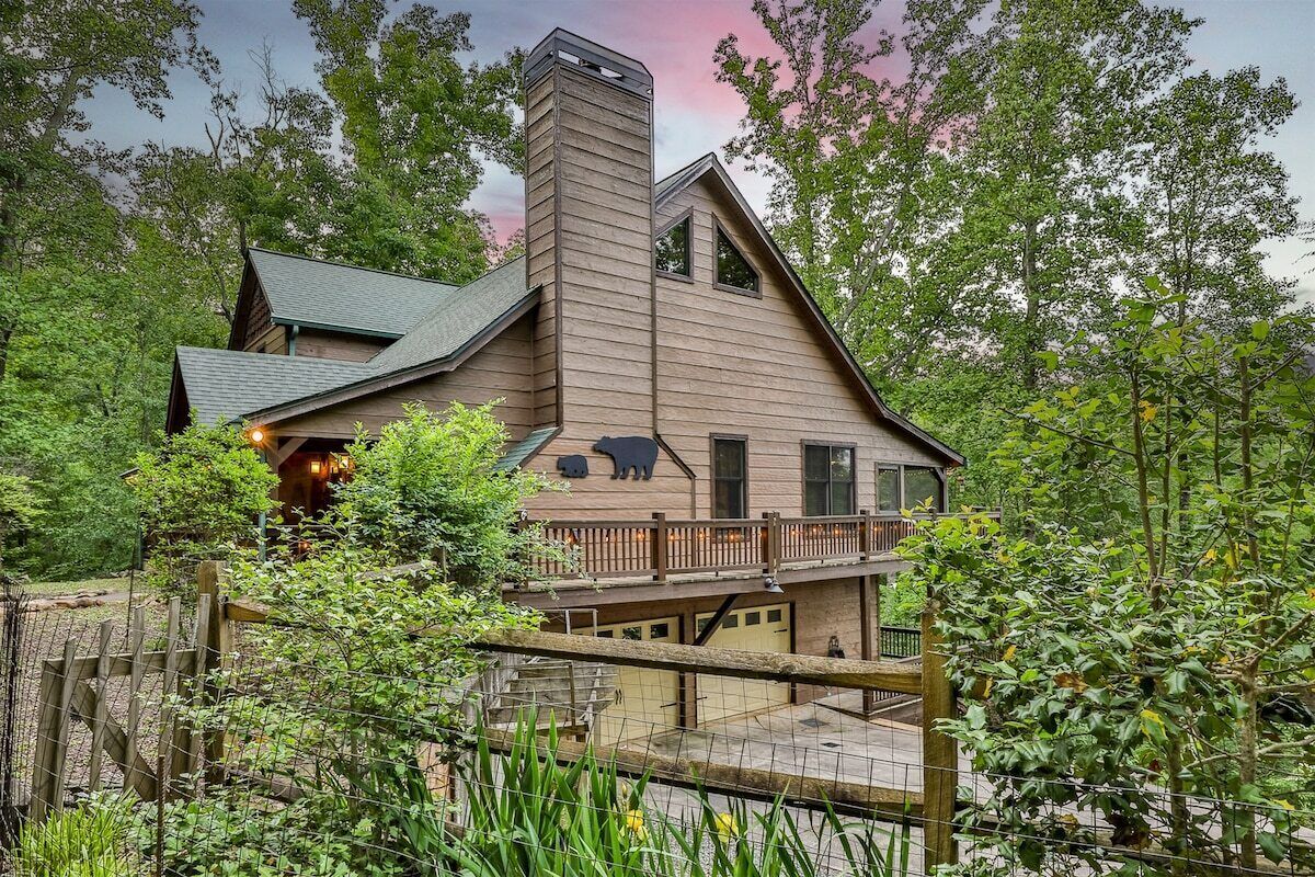 A two-story log cabin with a chimney, a balcony, and a bear symbol on the front.
