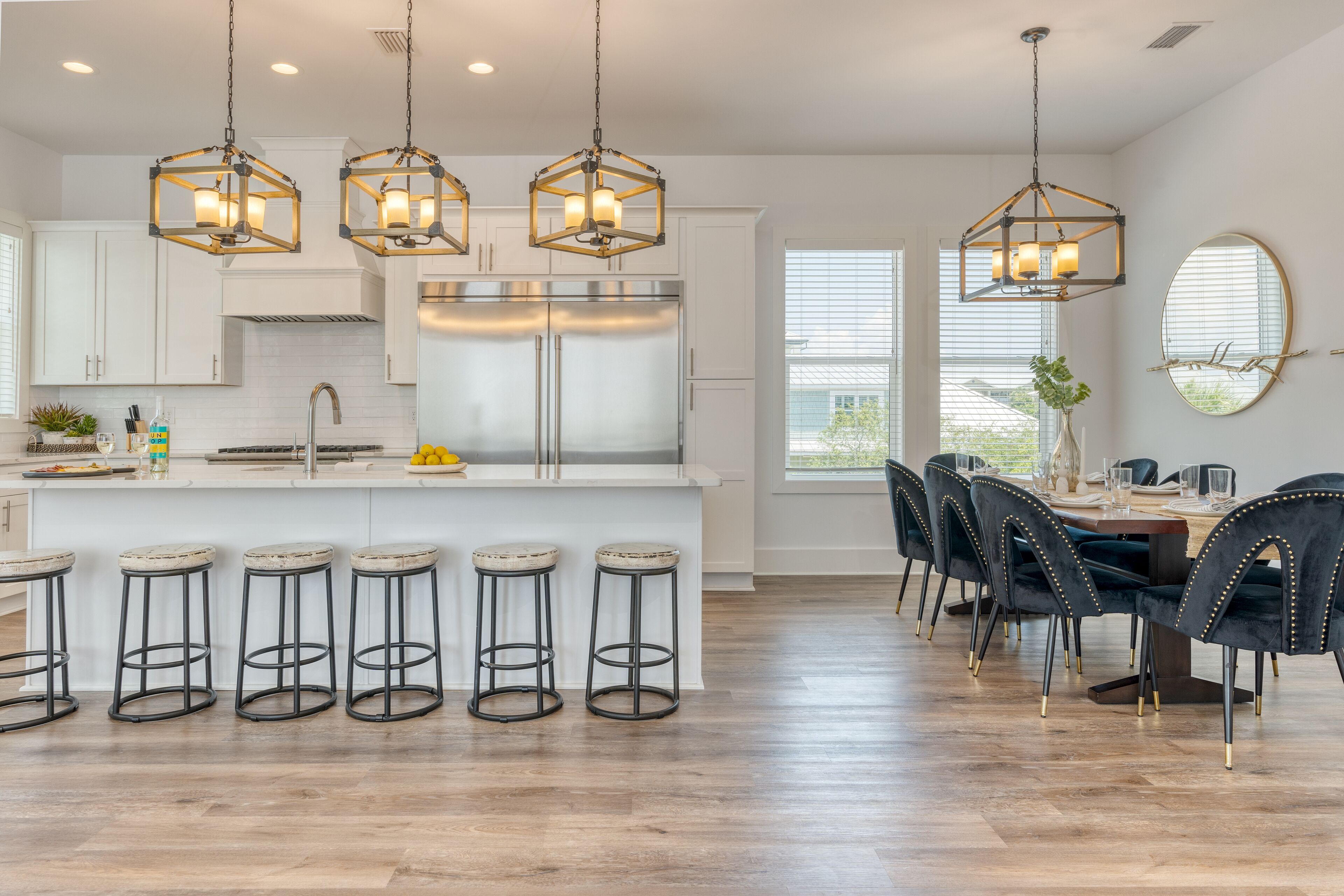 A modern kitchen with white cabinets, stainless steel appliances, and a central island with stools.