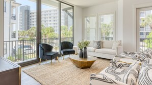 Ein modernes Wohnzimmer mit einem großen Fenster, einem Sofa, einem Couchtisch und zwei Sesseln.
