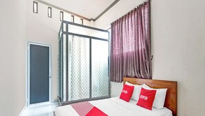 A bedroom with a bed, a sliding glass door, and a window with curtains. - OYO 90517 Homestay Wonosobo Asri (Wonosobo)