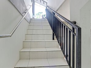 Un escalier avec des marches blanches et des rampes noires, menant à l’étage supérieur.