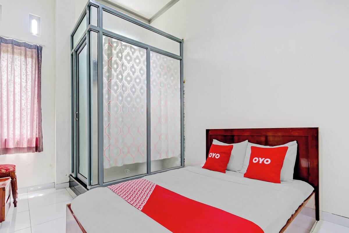 Een hotelkamer met een bed, een kledingkast en een raam met gordijnen.