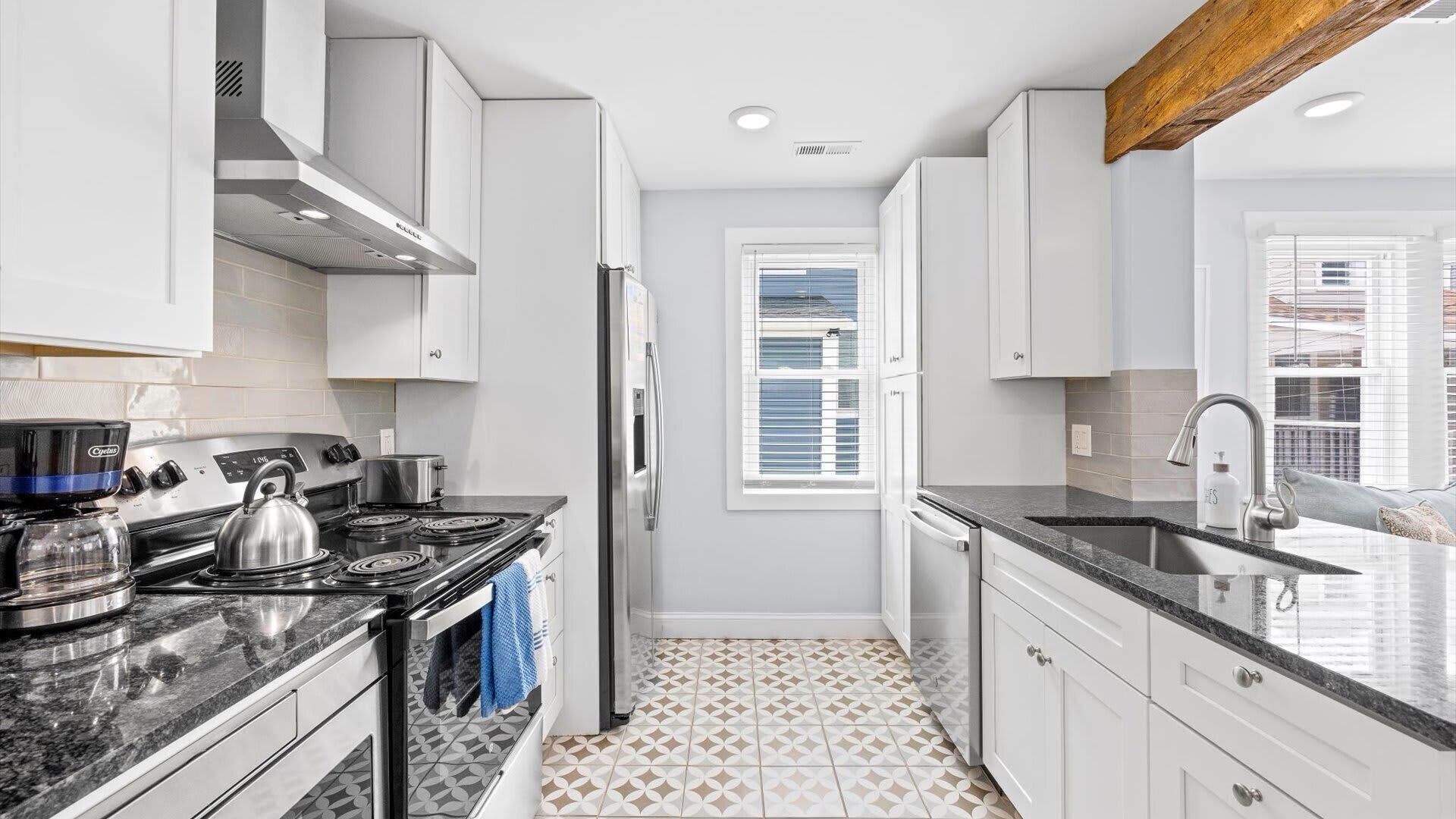 A modern kitchen with white cabinets, a black stove, and a stainless steel sink.