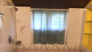 A small bathroom with a shower, a window with curtains, and a tiled floor. - Manikkal Bungalow Uphill Cottage Large (Mananthavady)