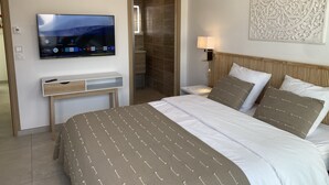 A hotel room with a bed, a TV mounted on the wall, a bedside table, and a decorative wall piece.