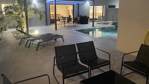 A poolside area with lounge chairs, a small pool, and a covered seating area with ambient lighting.