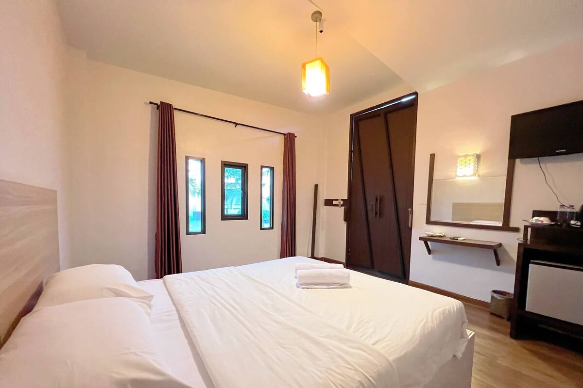 A hotel room with a bed, a wardrobe, a desk, and a mirror.