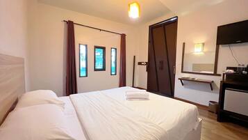 A hotel room with a bed, a wardrobe, a desk, and a mirror.