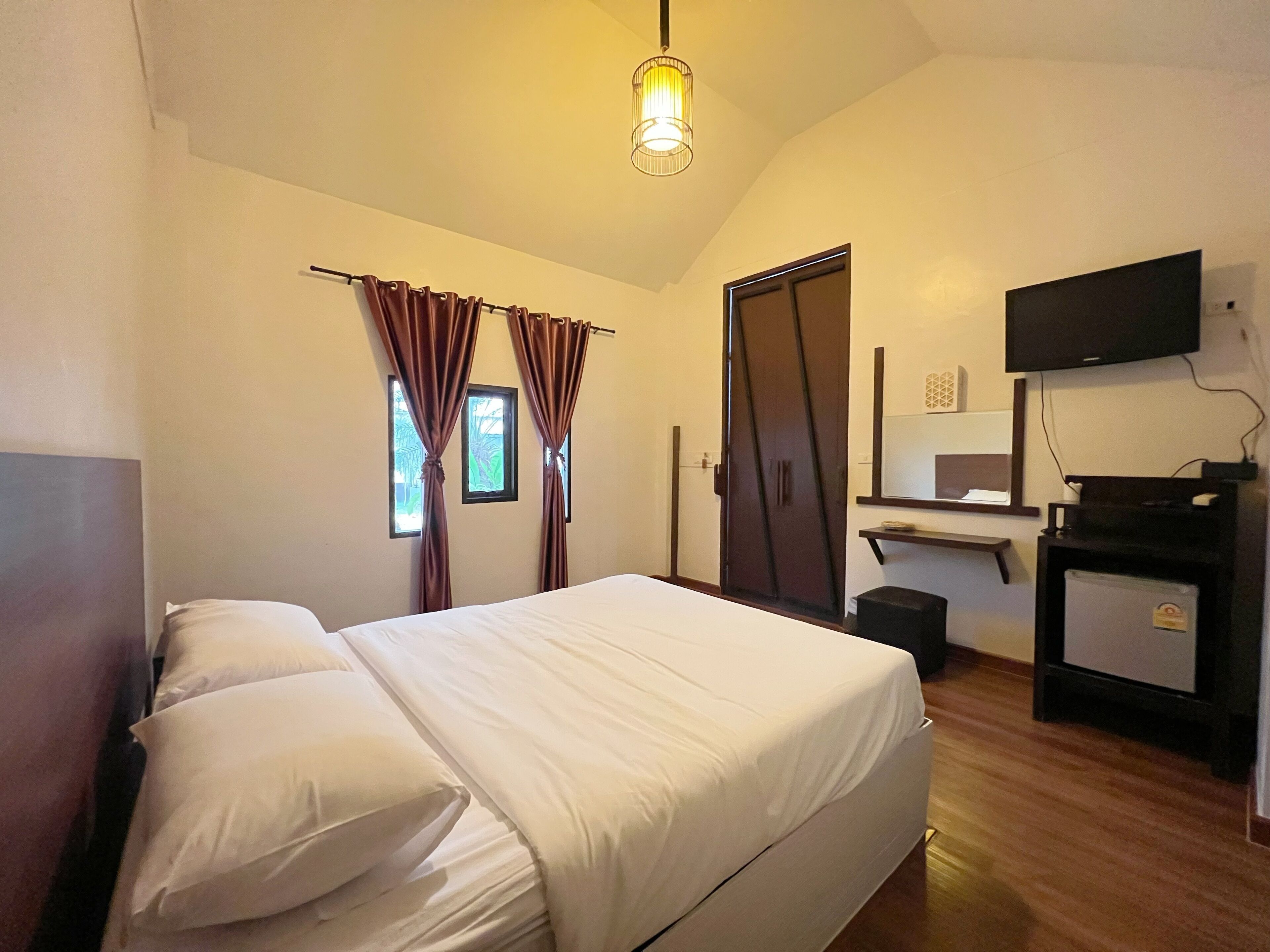 A bedroom with a bed, a desk, a television, and a wardrobe.
