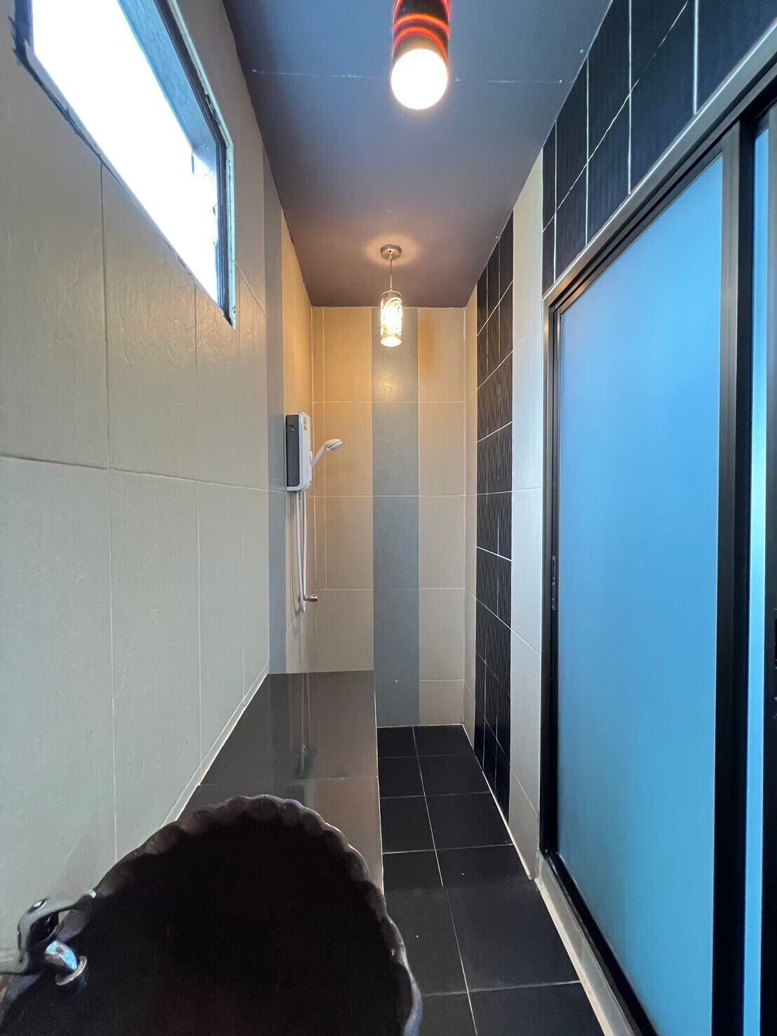 A narrow hallway with a hand dryer on the left, a light fixture on the ceiling, and a blue wall on the right.
