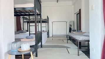 Habitación tipo dormitorio con literas, una mesita con botellas y un espejo.