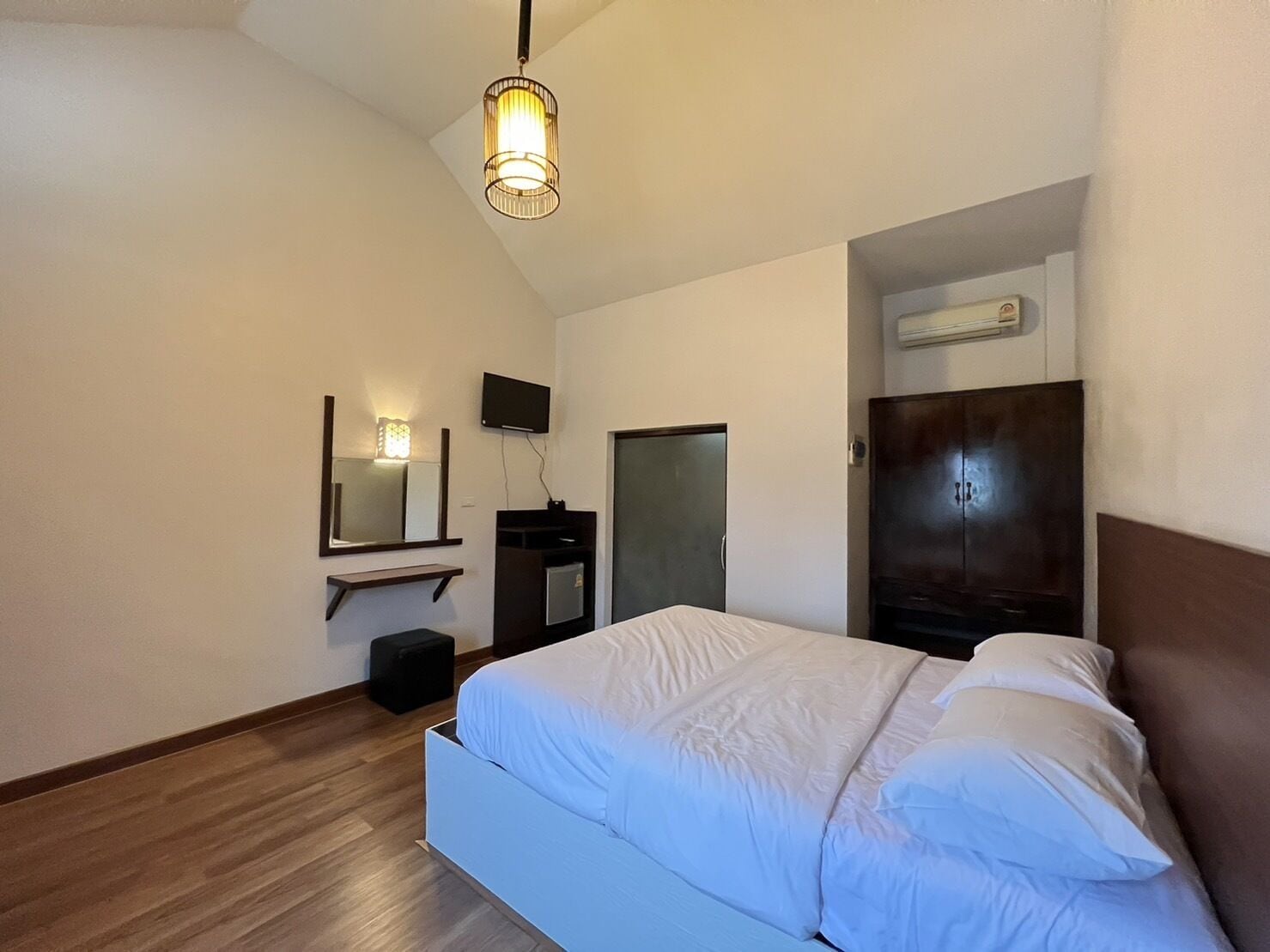 Ein Schlafzimmer mit einem Bett, einem Spiegel, einem Fernseher und einem Kleiderschrank.