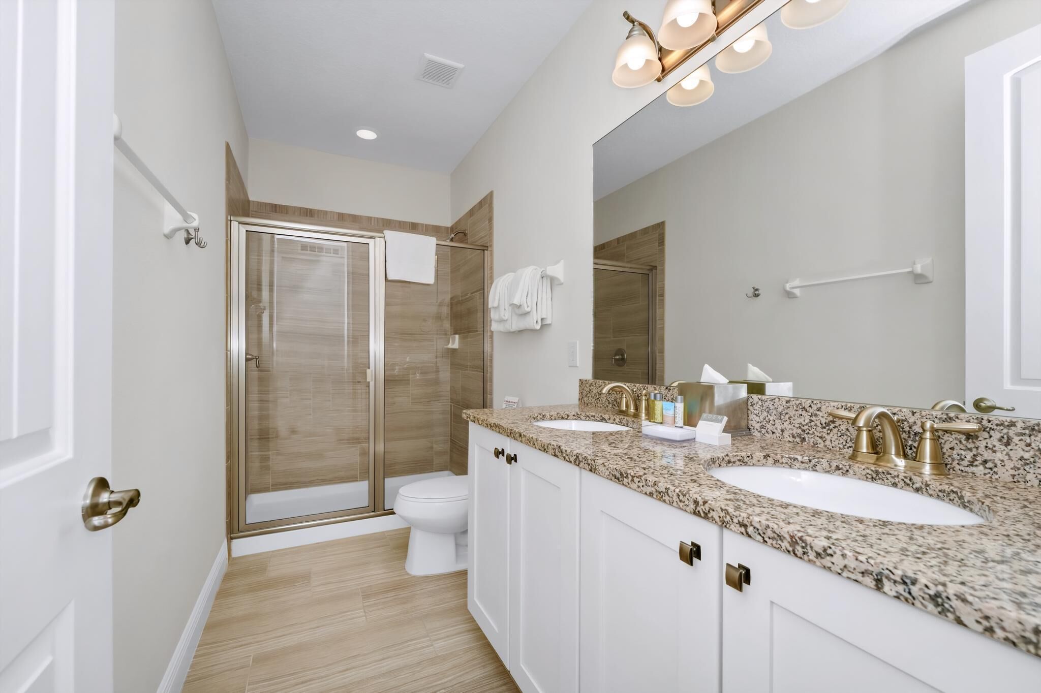 Une salle de bain moderne avec deux lavabos, une douche et un grand miroir.