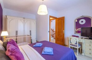 A bedroom with a bed, a dresser, a television, and a door leading to another room. - Villa Ruxandra (CT)