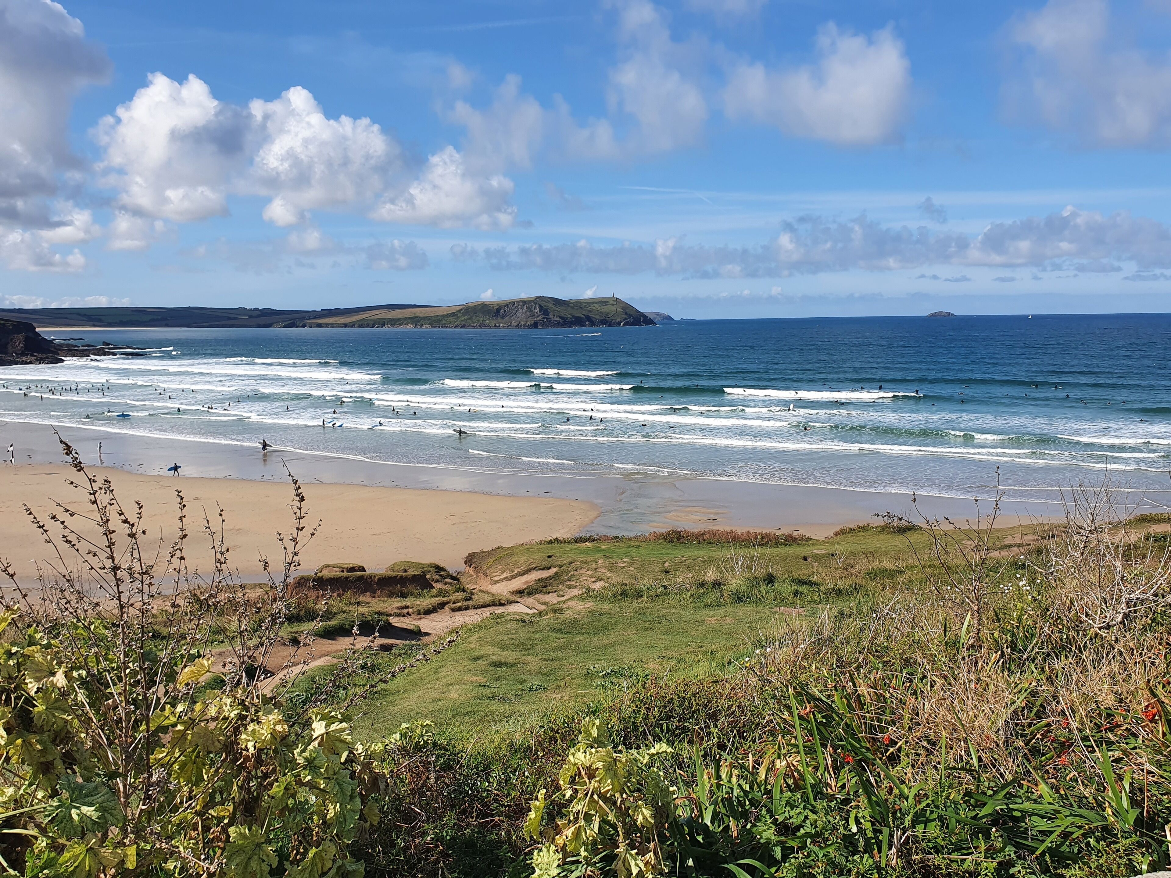 Eine Küstenlandschaft mit Strand, Wellen und einer fernen Insel.