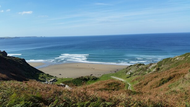 A coastal landscape with a beach, grassy hills, and a clear view of the ocean. - Exquisite Shepherd's HUT With HOT TUB - Between Moor and sea (Camelford)