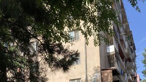 Un immeuble doté de nombreux balcons, une pharmacie et un petit kiosque avec une vitrine en verre.