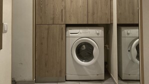Une buanderie équipée de deux machines à laver, de meubles en bois et d’un luminaire.