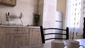 Une cuisine avec des meubles de rangement en bois, une chaise noire et deux tasses blanches posées sur une table en bois.