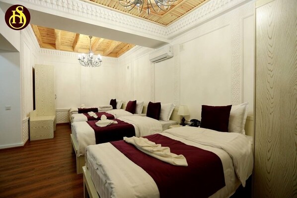 Una habitación de hotel con cuatro camas, un candelabro y techo de madera.