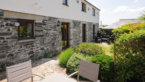 A building with stone walls and a white facade, featuring a door and windows. - Great Brightor Cob Barn (Bodmin)