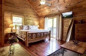 A wooden cabin bedroom with a bed, a television, and a desk. - Yourcation® Awaits in Spectacular, 6-Bedroom Cabin! (Sevierville)