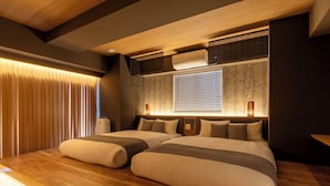 Un dormitorio moderno con dos camas, suelo de madera, un ventanal con persianas y un equipo de aire acondicionado.