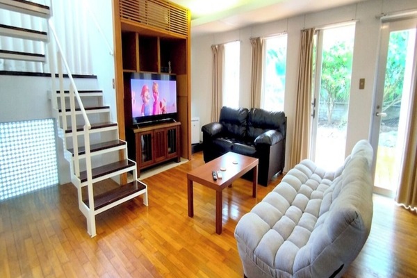 The spacious living room is equipped with a TV, two types of sofas, and a low table, making it perfect for staying with friends or family. Large windows and glass doors let in plenty of natural light. Enjoy an extraordinary time in this comfortable and cozy space.