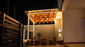 Un patio al aire libre con una pérgola de madera, un ventilador y asientos.
