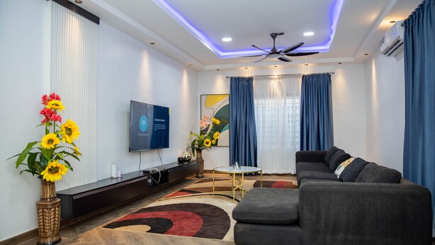Una sala de estar moderna con un sofá, televisor y plantas decorativas.