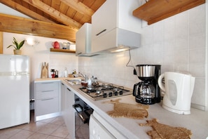 Una cocina equipada con estufa a gas, cafetera y hervidor.