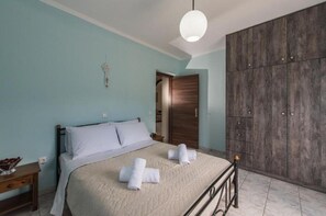 Ein Schlafzimmer mit Bett, Kleiderschrank, Nachttisch und einer Pendelleuchte.