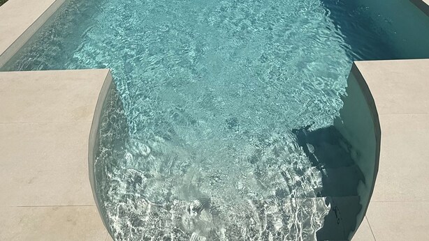 Une piscine à l’eau claire, dont les bords sont recouverts de carreaux.