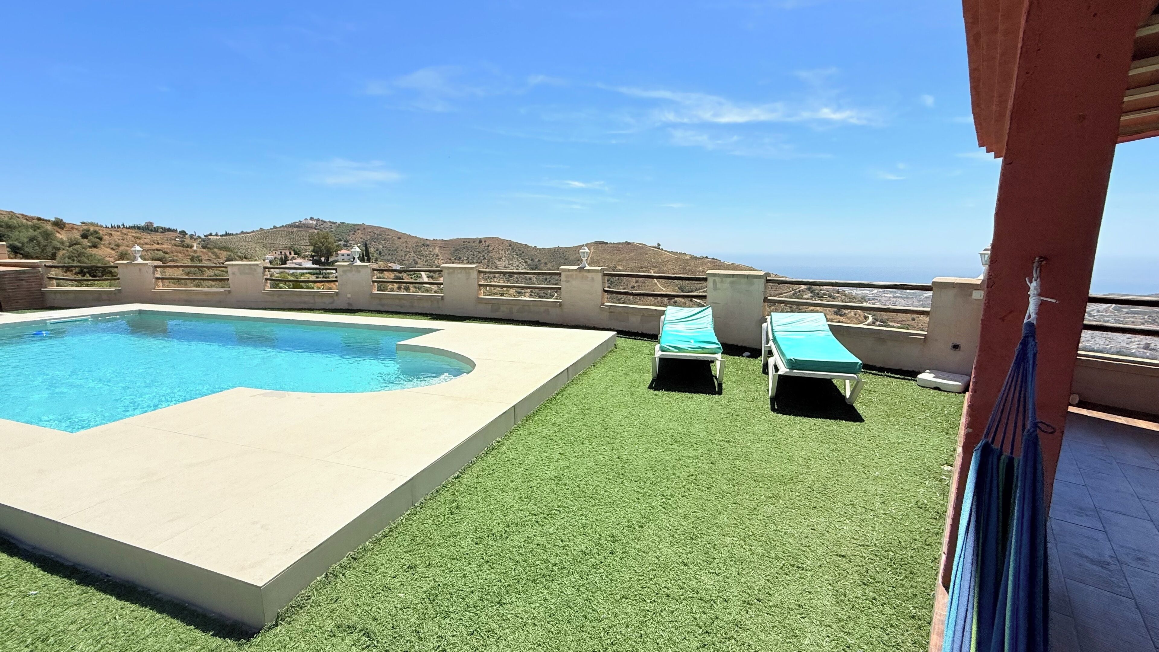 A swimming pool with two lounge chairs and a view of the sea.