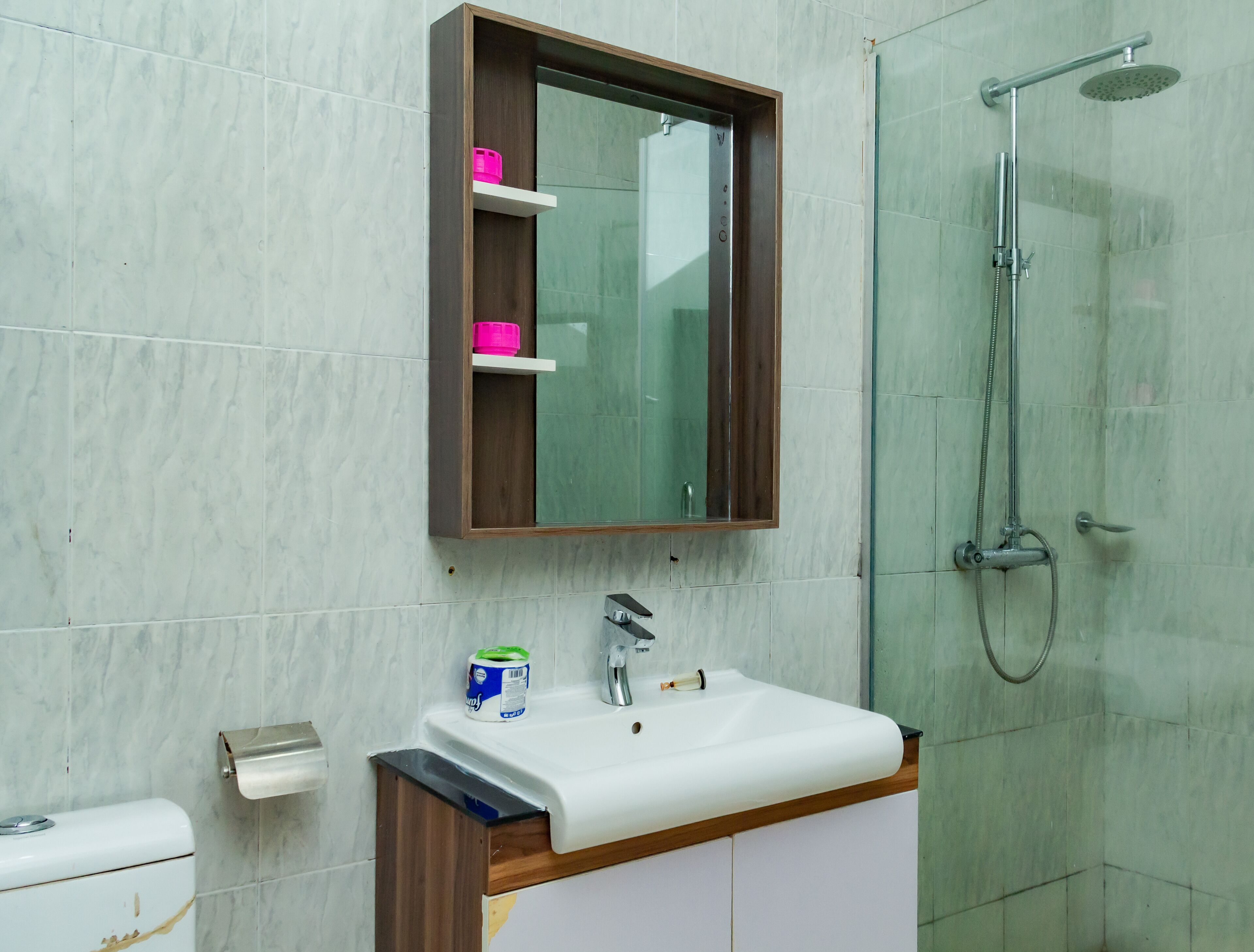 A bathroom with a white sink, a mirror above it, and a shower area to the right.