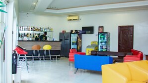 A bar area with a counter, stools, and a refrigerator. - The Point Hotel and Suites (Jos)
