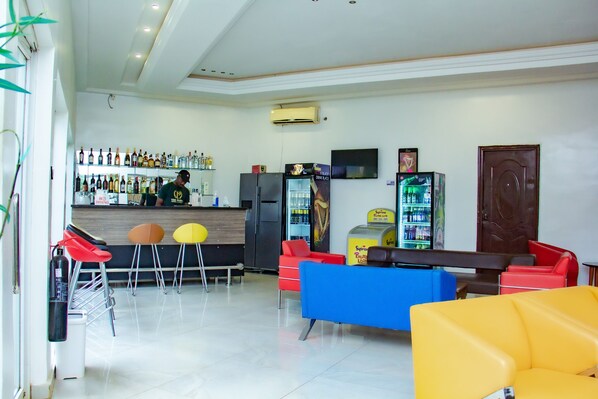 A bar area with a counter, stools, and a refrigerator.