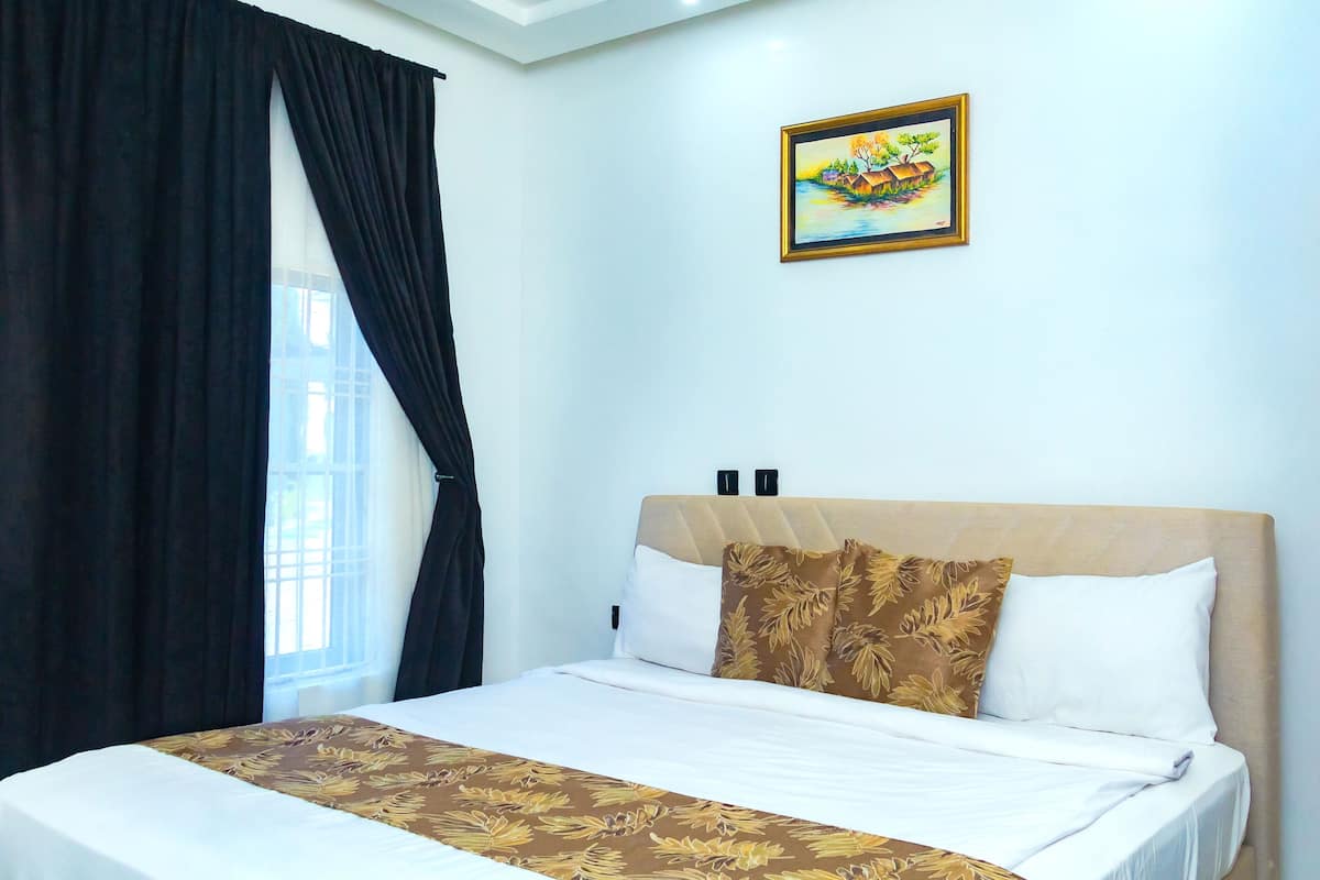 A neatly made bed with a floral bedspread, a headboard, and two pillows.