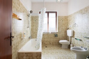 A bathroom with a bathtub, toilet, and bidet.