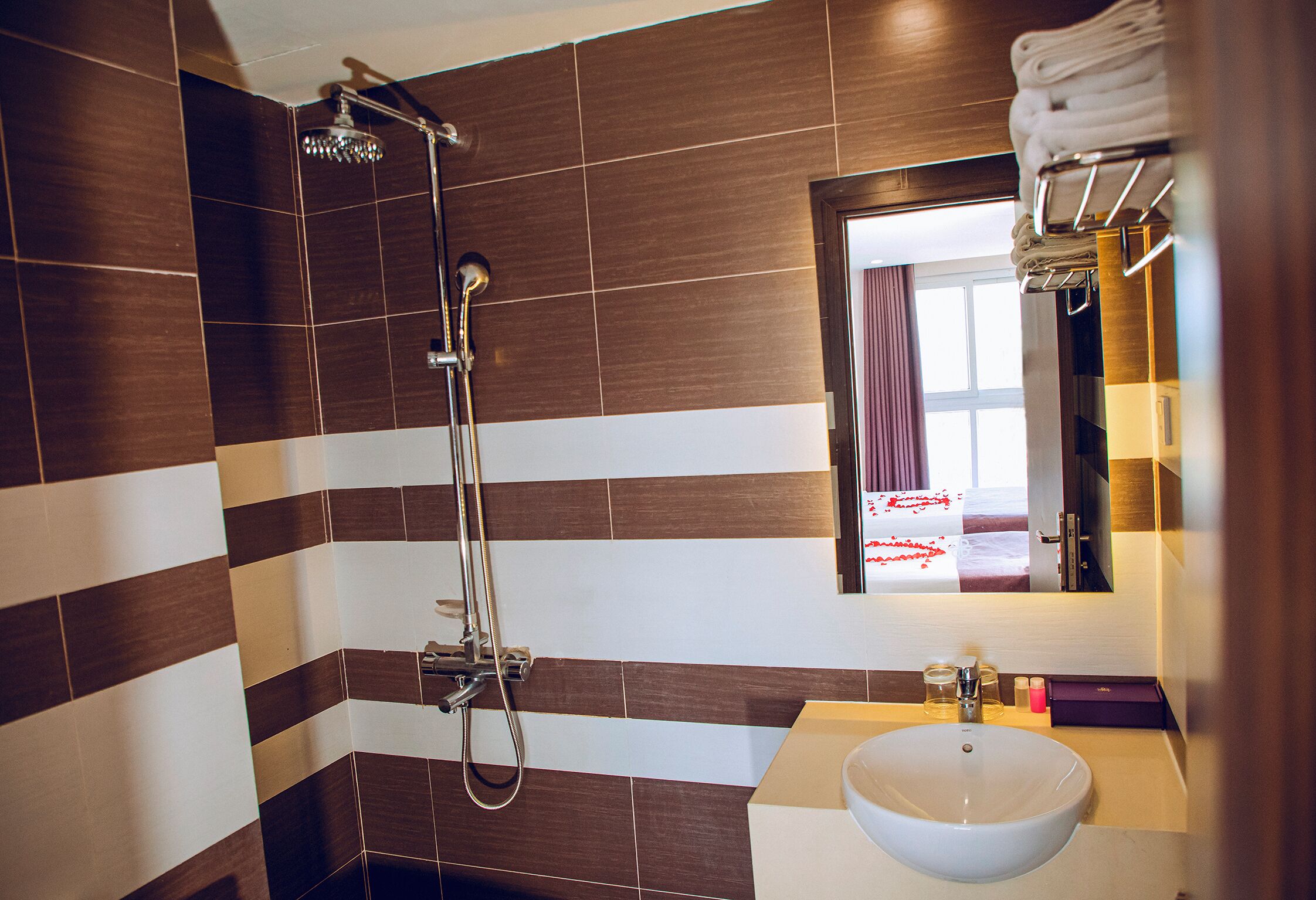 Een badkamer met een douche, een wastafel en een spiegel.