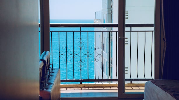 Un balcón con vista al mar y un edificio al fondo.