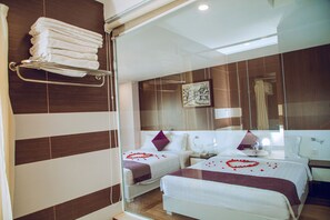 A hotel room with two beds, a glass shower enclosure, a towel rack, and a painting on the wall. - Morris Hotel Nha Trang (Nha Trang)