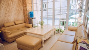 Una sala de estar moderna con un sofá beige, una mesa de centro y vistas a la ciudad a través de amplias ventanas.