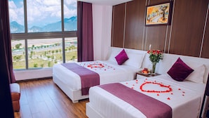 Una habitación de hotel con dos camas, un ventanal con vistas a la montaña y un cuadro en la pared.